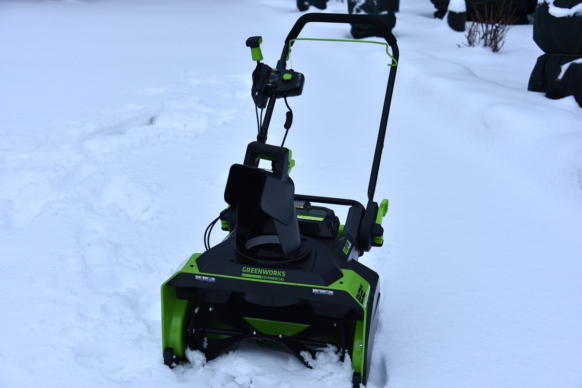 аккумуляторный снегоуборщик Greenworks на фоне мокрого снега